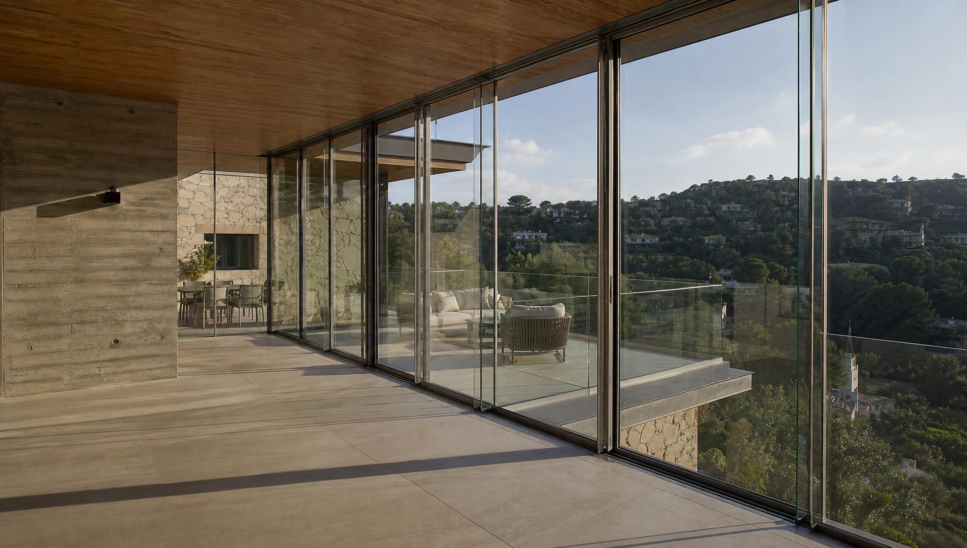Modern bir konutun geniş terasında uygulanmış sürme cam balkon sistemi